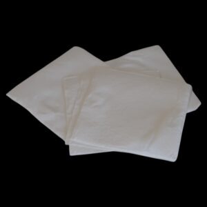 Two white folded cloth napkins on a black background.