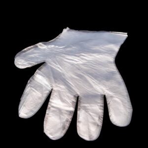 A single white disposable glove against a black background.