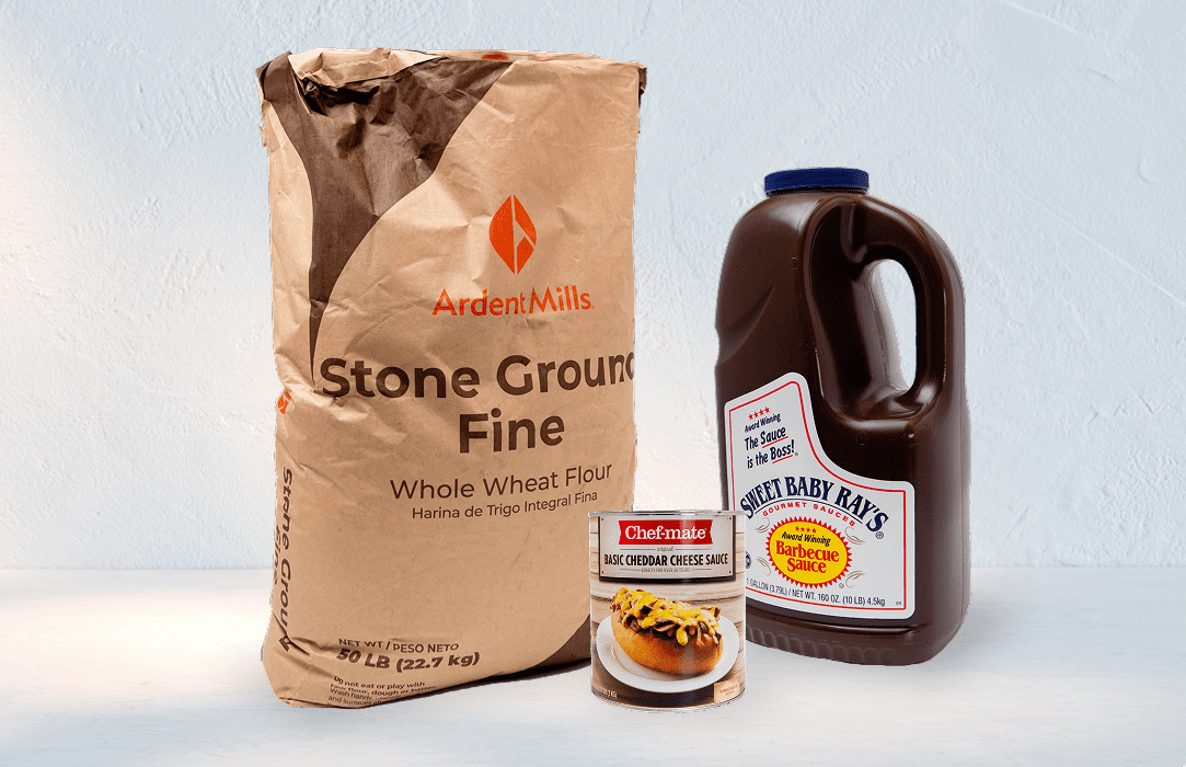 A bag of stone-ground fine whole wheat flour, syrup, and a bowl of pancakes.