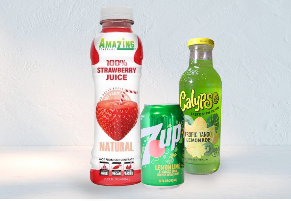 Three different fruit juice and soda bottles on a white surface.
