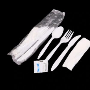 Disposable plastic cutlery set with fork, knife, spoon, napkin, and salt packet.